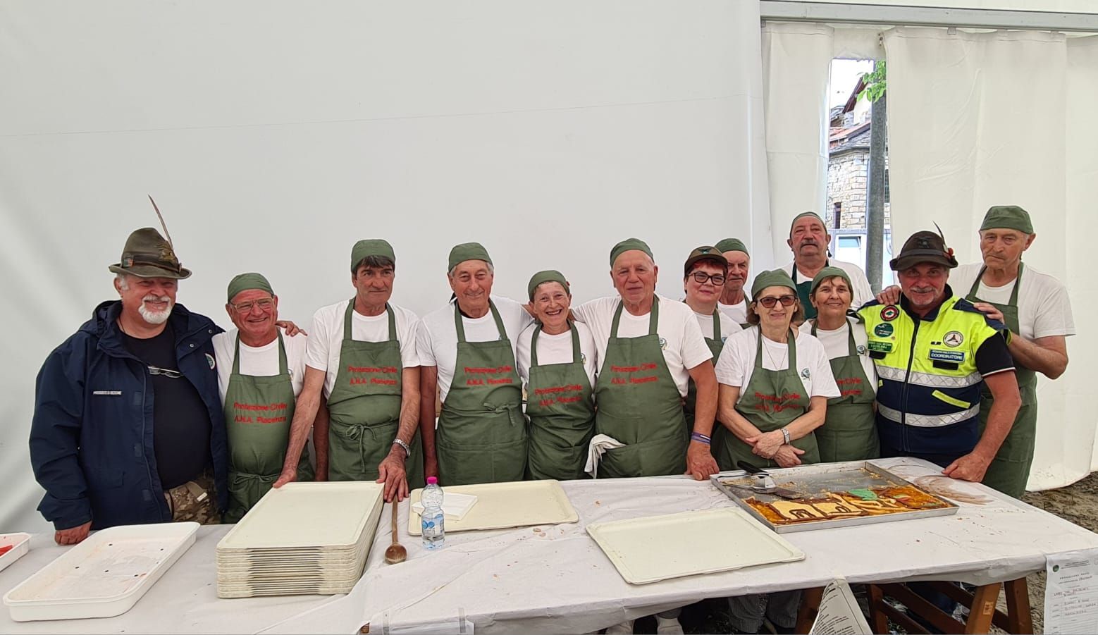 un gruppo di volontari della cucina con il presidente sezionale Gian Luca Gazzola (a sinistra) e  Franco Pavesi coordinatore dell'Unità di Protezione Civile Ana. Foto di Valerio Marangon