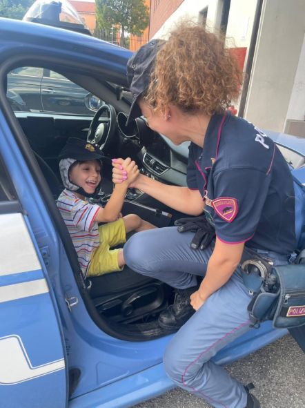 Il piccolo Paolo stringe la mano a una agente di polizia