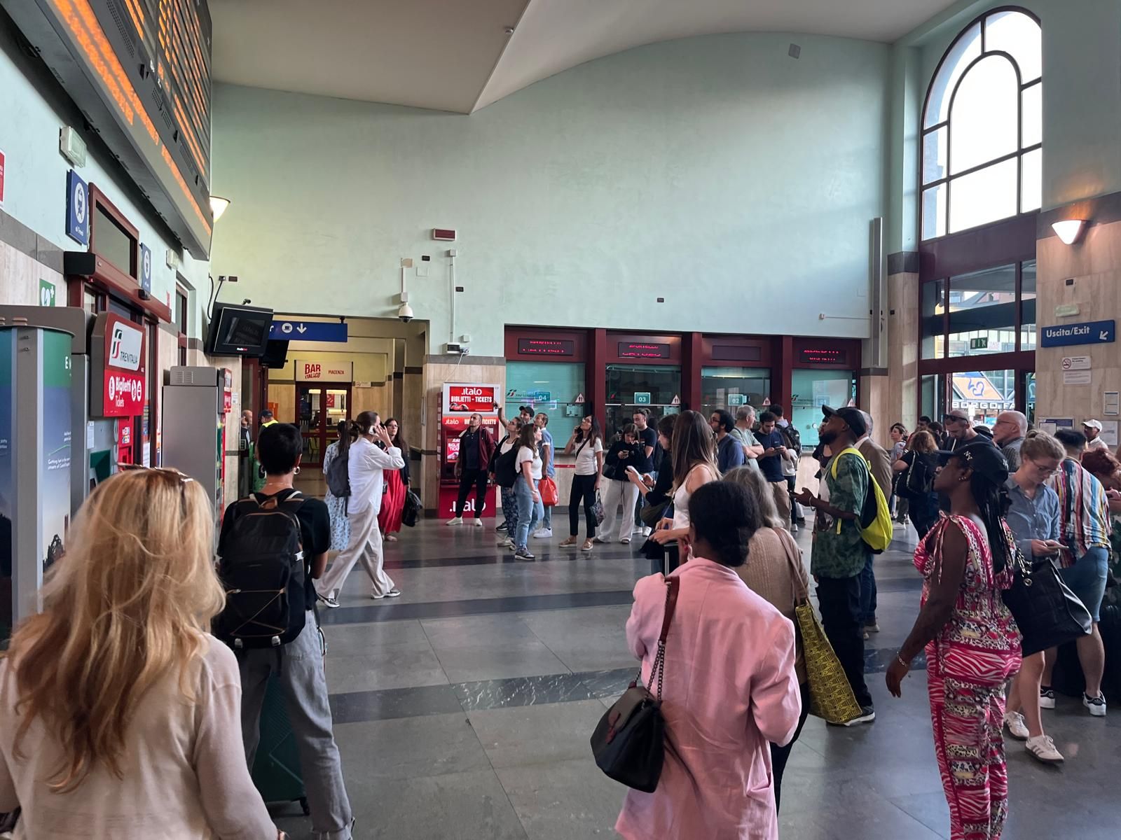 I passeggeri davanti al tabellone degli orari della stazione di Piacenza
