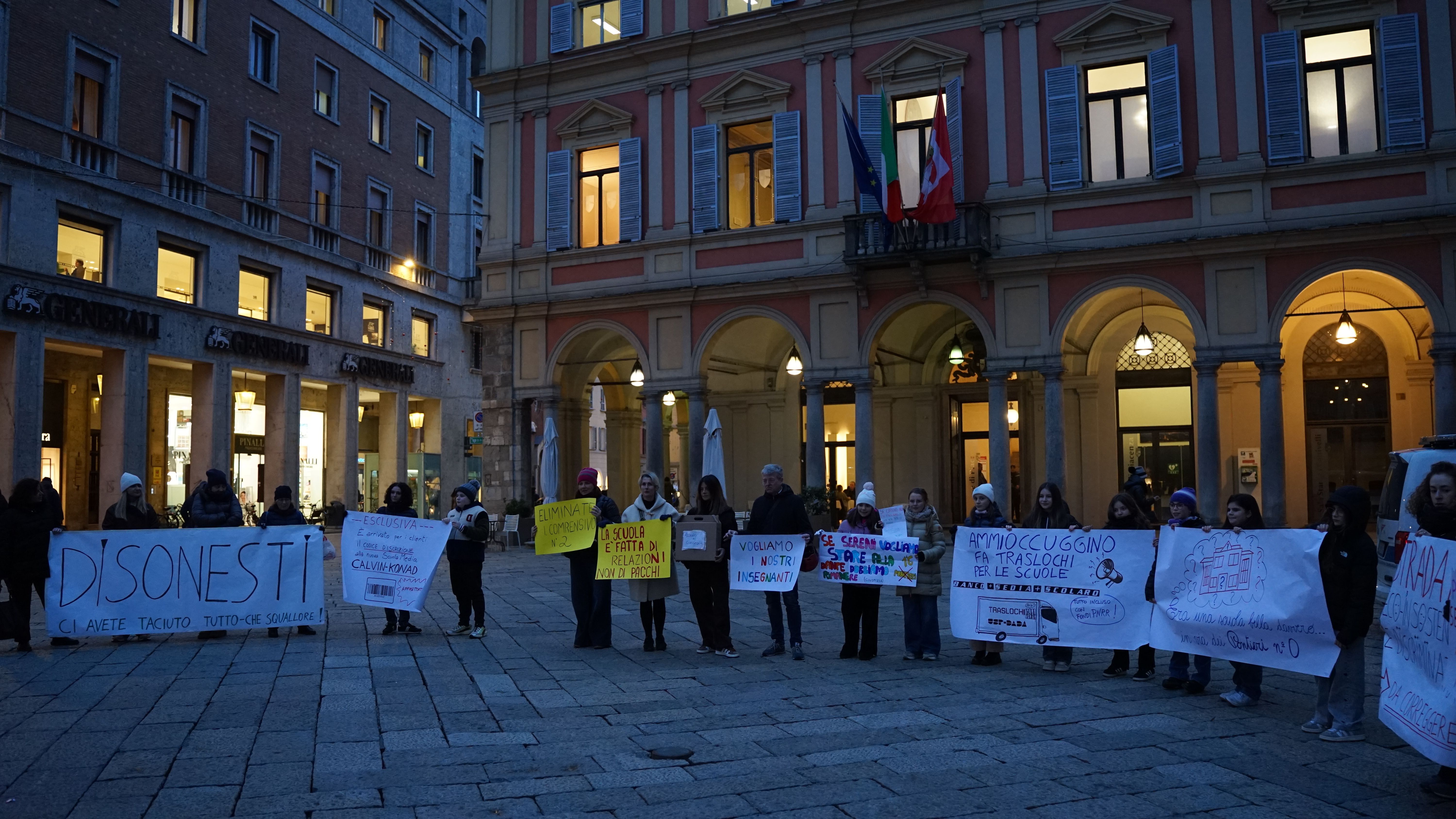 Alcuni dei manifestanti espongono cartelli. Luci accese in Consiglio comunale (foto Grisoli)