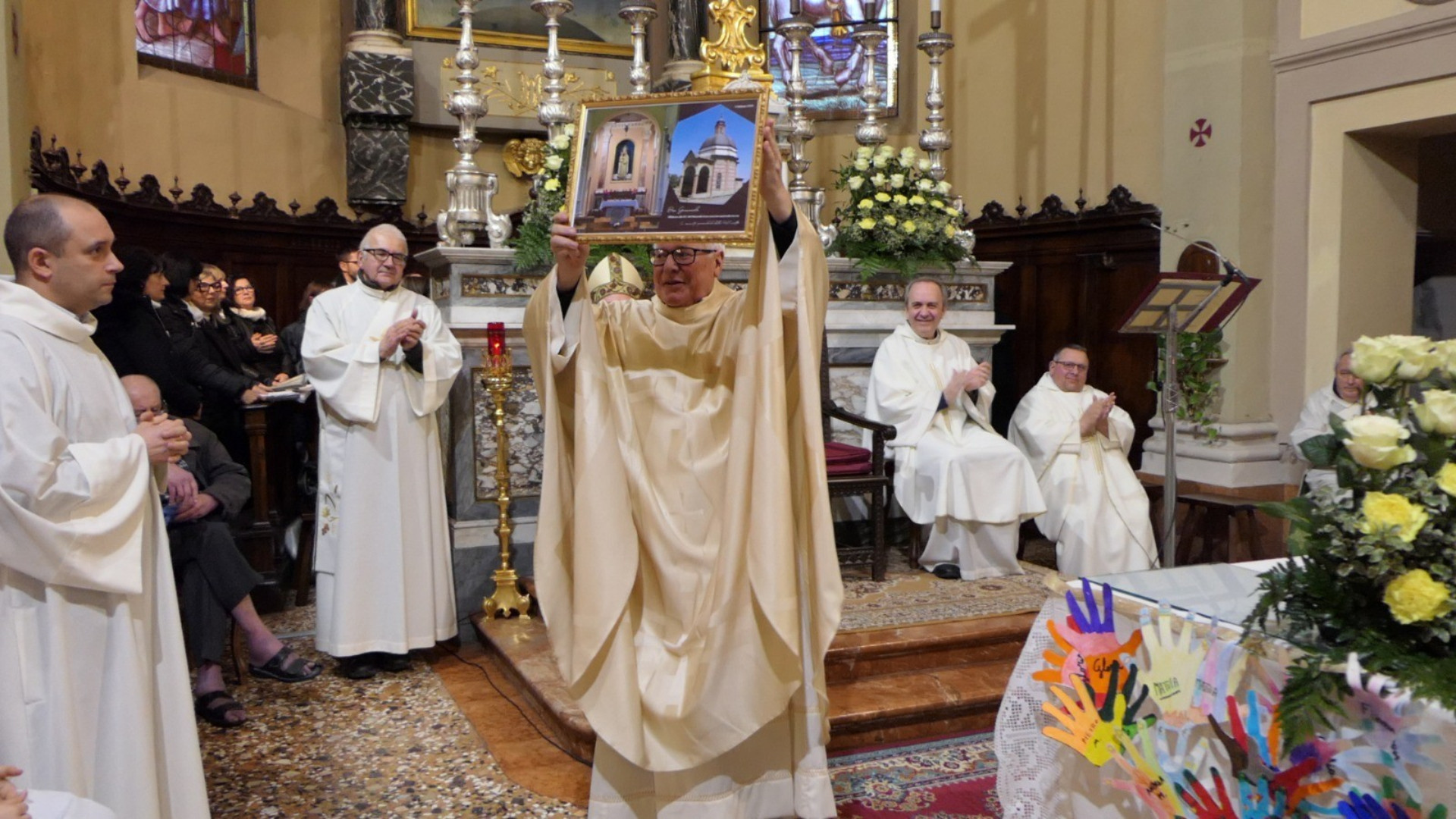 Don Giancarlo Plessi mostra un'immagine del santuario del Pilastrello che gli è stata donata in occasione della messa di insediamento