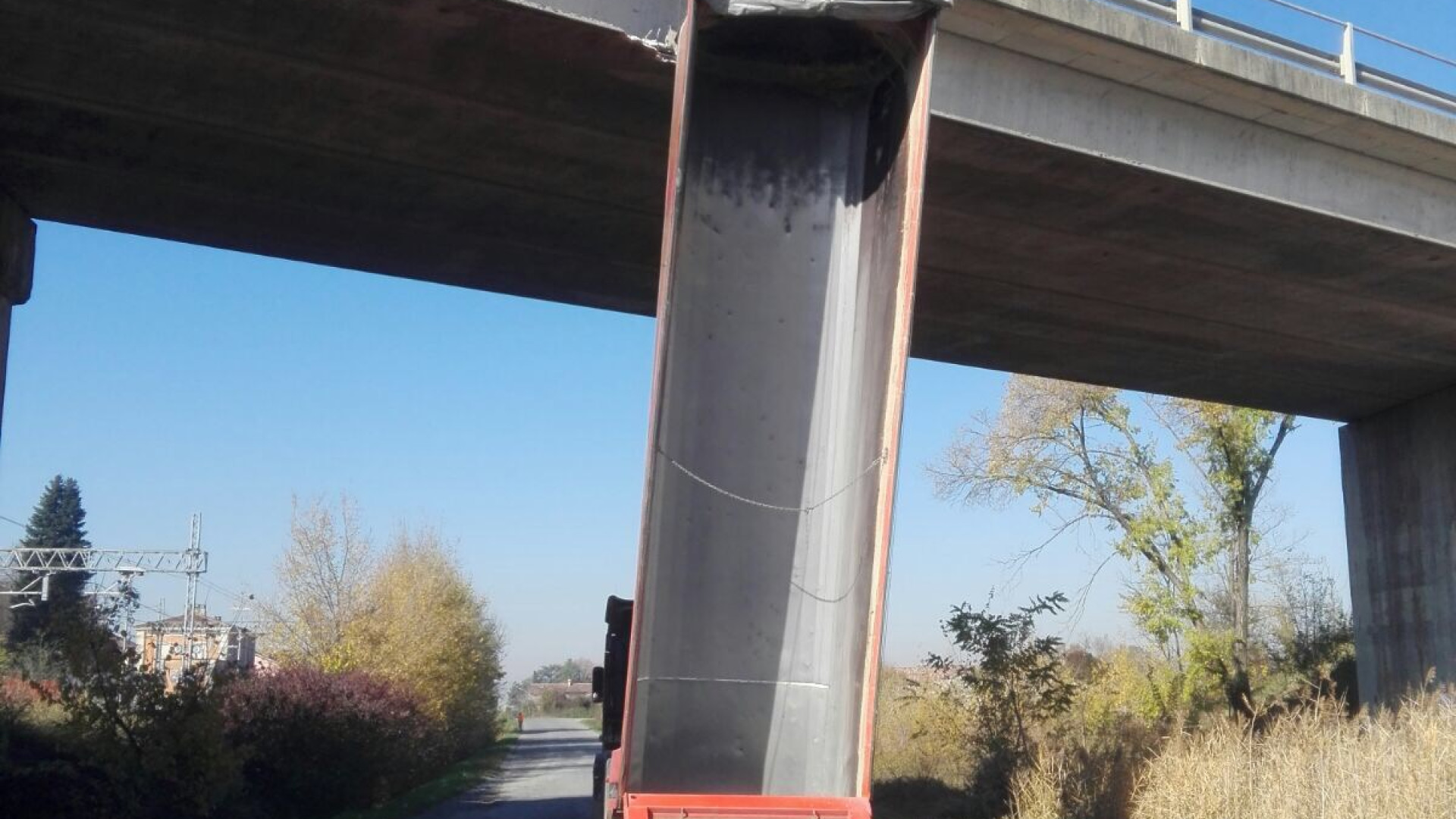 Autista dimentica il rimorchio alzato: il camion si incastra nel ponte